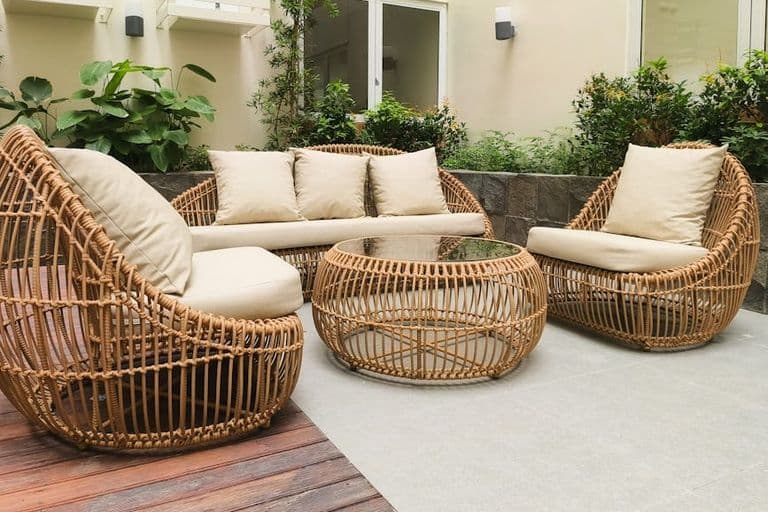 Outdoor seating with rattan furniture set in a lush garden patio, ideal for relaxation and gatherings.