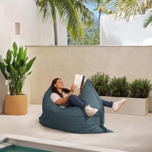 Femme lisant sur pouf géant imperméable près piscine tropicale